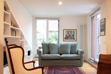 Esempio di un soggiorno contemporaneo di medie dimensioni con libreria, pareti bianche, pavimento in legno verniciato, pavimento marrone e con abbinamento di mobili antichi e moderni