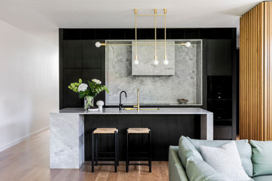 Design ideas for a mid-sized contemporary galley kitchen in Sydney with an undermount sink, flat-panel cabinets, black cabinets, grey splashback, black appliances, medium hardwood floors, with island, beige floor and grey benchtop.