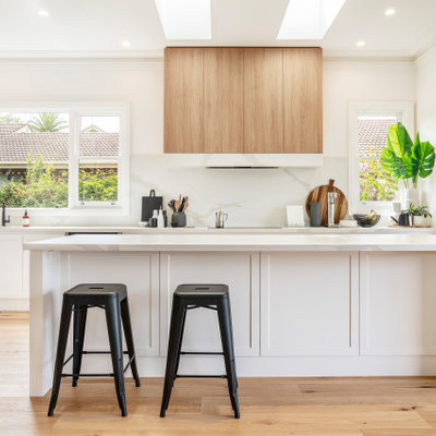 Open concept kitchen - mid-sized transitional galley light wood floor and brown floor open concept kitchen idea in Melbourne with a double-bowl sink, shaker cabinets, white cabinets, marble countertops, white backsplash, marble backsplash, stainless steel appliances, an island and white countertops