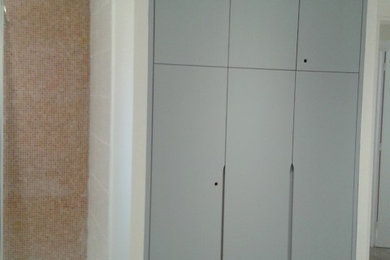 Cette photo montre un placard dressing tendance de taille moyenne avec un placard à porte affleurante et des portes de placard grises.