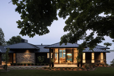 Large trendy black two-story stone and clapboard house exterior photo in Toronto with a hip roof, a metal roof and a black roof