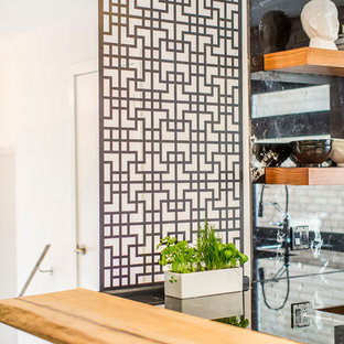 Mittelgroße Asiatische Küche in U-Form mit Vorratsschrank, Unterbauwaschbecken, flächenbündigen Schrankfronten, hellbraunen Holzschränken, Marmor-Arbeitsplatte, Küchenrückwand in Schwarz, Rückwand aus Marmor, Küchengeräten aus Edelstahl, Betonboden, Kücheninsel und grauem Boden in Toronto