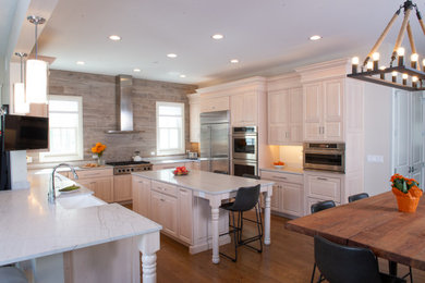 Open concept kitchen - large transitional u-shaped medium tone wood floor and brown floor open concept kitchen idea in Chicago with a farmhouse sink, raised-panel cabinets, light wood cabinets, quartzite countertops, brown backsplash, porcelain backsplash, stainless steel appliances, an island and gray countertops