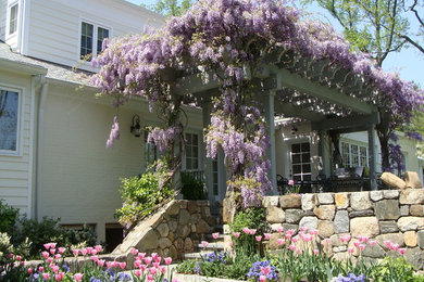 Patio kitchen - large traditional backyard stone patio kitchen idea in New York with a pergola