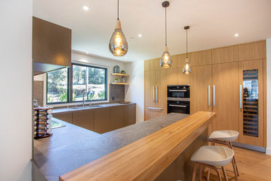 Moderne Küche ohne Insel in U-Form mit Unterbauwaschbecken, flächenbündigen Schrankfronten, Küchenrückwand in Grau, braunem Holzboden und grauer Arbeitsplatte in Sonstige