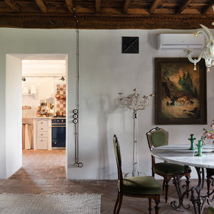 Inspiration pour une salle à manger bohème avec un mur blanc et un sol en brique.