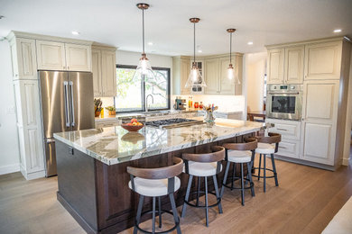 Open concept kitchen - large transitional single-wall medium tone wood floor and brown floor open concept kitchen idea in San Francisco with an undermount sink, raised-panel cabinets, white cabinets, quartzite countertops, gray backsplash, stone tile backsplash, stainless steel appliances, an island and green countertops