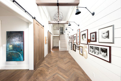 Inspiration for a large cottage medium tone wood floor, brown floor, exposed beam and shiplap wall hallway remodel in San Francisco with white walls