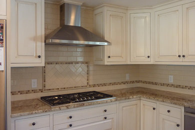 Inspiration for a timeless l-shaped medium tone wood floor eat-in kitchen remodel in Boston with recessed-panel cabinets, white cabinets, granite countertops, white backsplash, subway tile backsplash, stainless steel appliances and an island