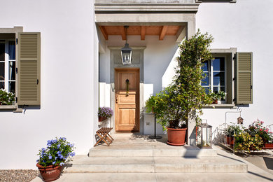 Esempio di una porta d'ingresso chic di medie dimensioni con una porta singola, una porta in legno bruno, pavimento in cemento, pavimento grigio e pareti beige