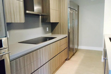 Kitchen - mid-sized modern porcelain tile kitchen idea in Miami with a single-bowl sink, flat-panel cabinets, medium tone wood cabinets, solid surface countertops, gray backsplash, stainless steel appliances and an island