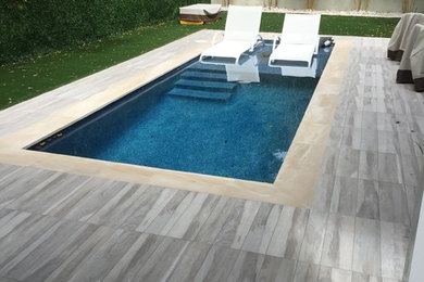 Small contemporary backyard rectangular lap pool in Miami with tile.