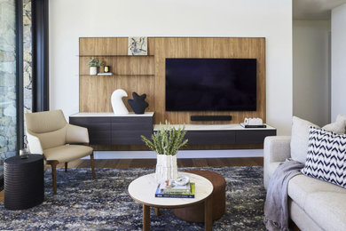 Modelo de salón abierto actual de tamaño medio con paredes blancas, suelo de madera clara y pared multimedia