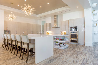Inspiration for a large contemporary l-shaped eat-in kitchen in Orlando with flat-panel cabinets, beige cabinets, quartz benchtops, beige splashback, stainless steel appliances, multiple islands, porcelain floors and beige floor.