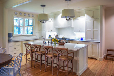 Open concept kitchen - large shabby-chic style l-shaped light wood floor open concept kitchen idea in Jacksonville with an undermount sink, shaker cabinets, white cabinets, quartz countertops, white backsplash, stainless steel appliances and an island