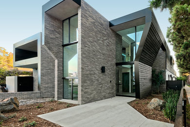 Example of a large trendy gray two-story brick exterior home design in Los Angeles