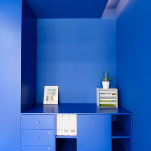 This is an example of a small modern home office and library in Other with a reading nook, blue walls, concrete flooring, a built-in desk and blue floors.