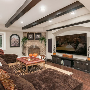 シカゴの巨大なトランジショナルスタイルのおしゃれな地下室 (半地下 (窓あり) 、グレーの壁、濃色無垢フローリング、コーナー設置型暖炉、レンガの暖炉まわり、茶色い床) の写真