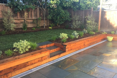 Mid-sized modern backyard partial sun formal garden in San Francisco with a retaining wall and natural stone pavers for summer.