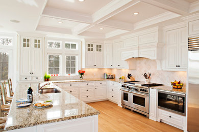 Inspiration for a coastal u-shaped light wood floor eat-in kitchen remodel in Boston with an undermount sink, recessed-panel cabinets, white cabinets, granite countertops, beige backsplash, ceramic backsplash and stainless steel appliances