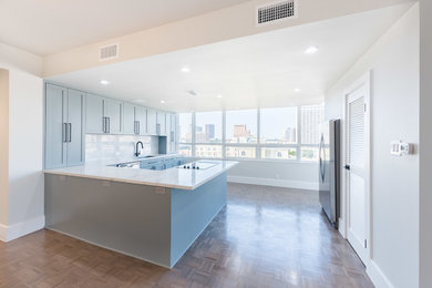 Inspiration for a large modern u-shaped eat-in kitchen remodel in Houston with an undermount sink, shaker cabinets, blue cabinets, quartz countertops, white backsplash, marble backsplash, stainless steel appliances, an island and white countertops