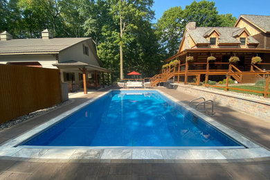 Pool landscaping - large rustic side yard concrete paver and rectangular pool landscaping idea in Milwaukee