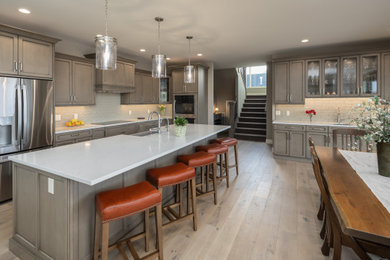 Large l-shaped light wood floor and beige floor kitchen photo in Other with an undermount sink, shaker cabinets, light wood cabinets, quartz countertops, beige backsplash, subway tile backsplash and white countertops