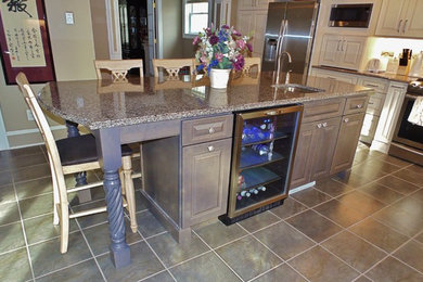 Inspiration for a large timeless l-shaped ceramic tile eat-in kitchen remodel in New York with an undermount sink, raised-panel cabinets, white cabinets, granite countertops, beige backsplash, ceramic backsplash, stainless steel appliances and an island