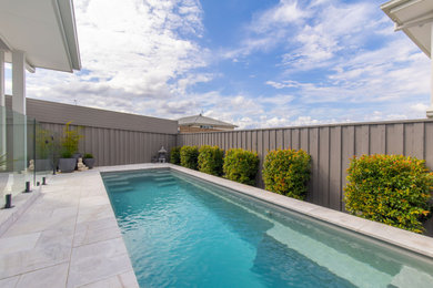 Photo of a mid-sized contemporary side yard rectangular pool in Newcastle - Maitland with with a pool and natural stone pavers.