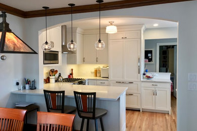 Eat-in kitchen - mid-sized traditional u-shaped medium tone wood floor eat-in kitchen idea in Minneapolis with recessed-panel cabinets, white cabinets, quartzite countertops, white backsplash, subway tile backsplash, stainless steel appliances and a peninsula