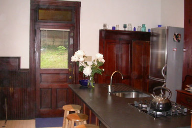 Mid-sized ornate kitchen pantry photo in Philadelphia with an undermount sink, raised-panel cabinets, dark wood cabinets and an island