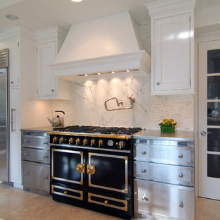 Design ideas for a mid-sized transitional l-shaped kitchen pantry in New York with a farmhouse sink, beaded inset cabinets, white cabinets, stainless steel benchtops, multi-coloured splashback, stone tile splashback, stainless steel appliances, porcelain floors and with island.