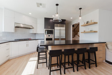 Eat-in kitchen - mid-sized modern u-shaped light wood floor and brown floor eat-in kitchen idea in San Francisco with an undermount sink, flat-panel cabinets, light wood cabinets, quartz countertops, gray backsplash, porcelain backsplash, stainless steel appliances, a peninsula and black countertops