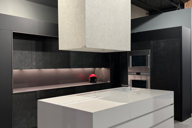 Example of a large trendy eat-in kitchen design in Other with an integrated sink, flat-panel cabinets, black cabinets, black appliances and an island
