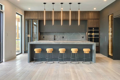 Eat-in kitchen - large modern light wood floor eat-in kitchen idea with flat-panel cabinets, dark wood cabinets, quartz countertops, gray backsplash, quartz backsplash, an island and gray countertops