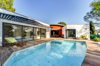 Exemple d'un couloir de nage arrière chic de taille moyenne et rectangle avec une terrasse en bois.