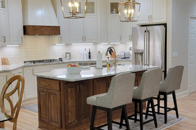 Inspiration for a mid-sized transitional light wood floor and beige floor eat-in kitchen remodel in Atlanta with an undermount sink, glass-front cabinets, white cabinets, quartz countertops, white backsplash, porcelain backsplash, stainless steel appliances, an island and multicolored countertops