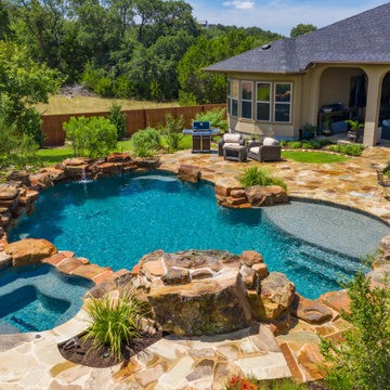 Freeform pool with weeping wall, grotto, and spa in San Antonio, Tx