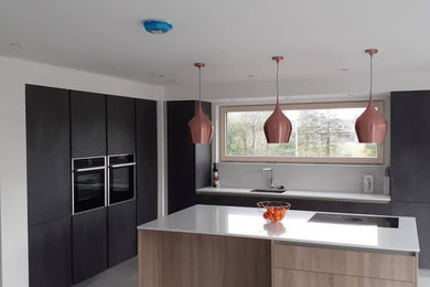 Photo of a medium sized modern l-shaped open plan kitchen in Other with black cabinets, quartz worktops, an island and white worktops.
