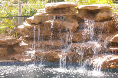 Pool fountain - transitional backyard stone natural pool fountain idea in Miami