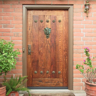 フェニックスの中サイズの片開きドアラスティックスタイルのおしゃれな玄関ドア (オレンジの壁、コンクリートの床、木目調のドア) の写真