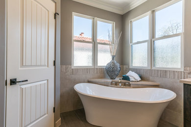 Example of a mid-sized master beige tile and stone tile porcelain tile and brown floor freestanding bathtub design in San Francisco with dark wood cabinets, a one-piece toilet, brown walls, an undermount sink and beige countertops