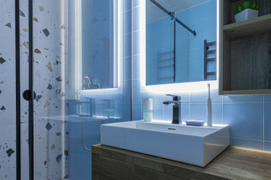 Пример оригинального дизайна: маленькая ванная комната в современном стиле с плоскими фасадами, фасадами цвета дерева среднего тона, душем в нише, разноцветной плиткой, керамической плиткой, синими стенами, полом из керамической плитки, душевой кабиной, настольной раковиной, столешницей из дерева, разноцветным полом, душем с раздвижными дверями, коричневой столешницей, зеркалом с подсветкой, тумбой под одну раковину и подвесной тумбой для на участке и в саду