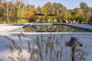 Modelo de piscina contemporánea rectangular en patio trasero con adoquines de hormigón