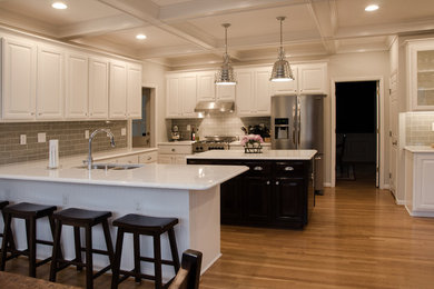 Large transitional u-shaped light wood floor eat-in kitchen photo in Raleigh with an undermount sink, raised-panel cabinets, white cabinets, quartzite countertops, gray backsplash, glass tile backsplash, stainless steel appliances and an island