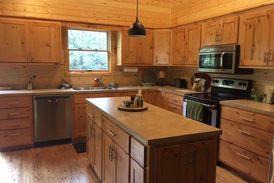 Large mountain style l-shaped medium tone wood floor and brown floor kitchen photo in Other with a double-bowl sink, shaker cabinets, light wood cabinets, solid surface countertops, brown backsplash, wood backsplash and stainless steel appliances