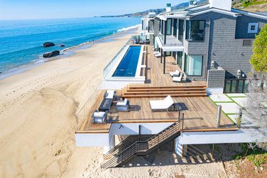 Modelo de terraza costera grande en patio trasero con barandilla de vidrio
