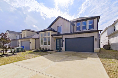 Example of a mid-sized trendy beige two-story mixed siding house exterior design in Houston with a shingle roof and a black roof