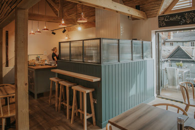 Offene Moderne Küche in L-Form mit Kassettenfronten, blauen Schränken, Arbeitsplatte aus Holz, Küchenrückwand in Weiß, Rückwand aus Holz, Kücheninsel und brauner Arbeitsplatte in Essex
