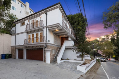 Large minimalist white two-story stucco and board and batten house exterior photo in Los Angeles with a tile roof and a red roof